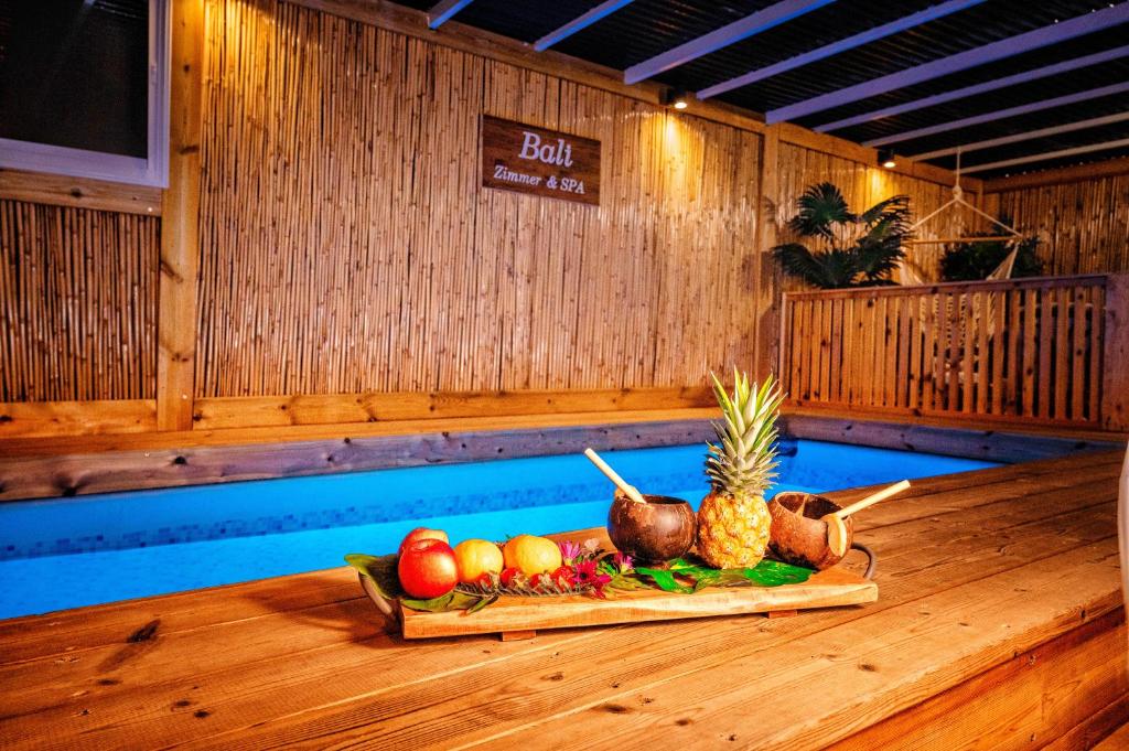 una bandeja de fruta en una mesa de madera en una piscina en bali carmel zimmer & spa en Dāliyat el Karmil