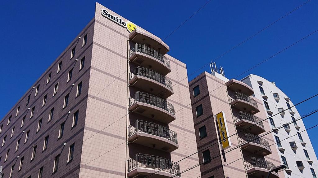 wysoki budynek z znakiem na boku w obiekcie Smile Hotel Tokyo Shinkoiwa w Tokio