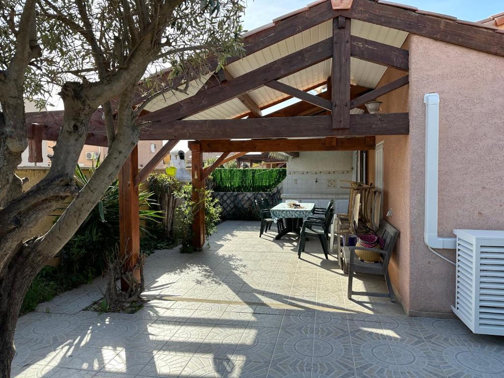 une pergola en bois avec une table et des chaises sur une terrasse dans l'établissement HOLIDAYLAND VILLA T3 304 MEZZANINE 9 couchages climatisé NARBONNE PLAGE, à Narbonne-Plage