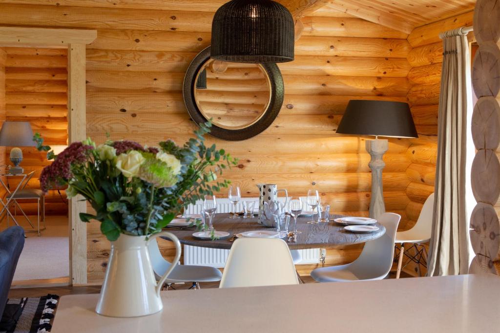 a dining room with a table with a vase of flowers at Owl's Nest in Foxton