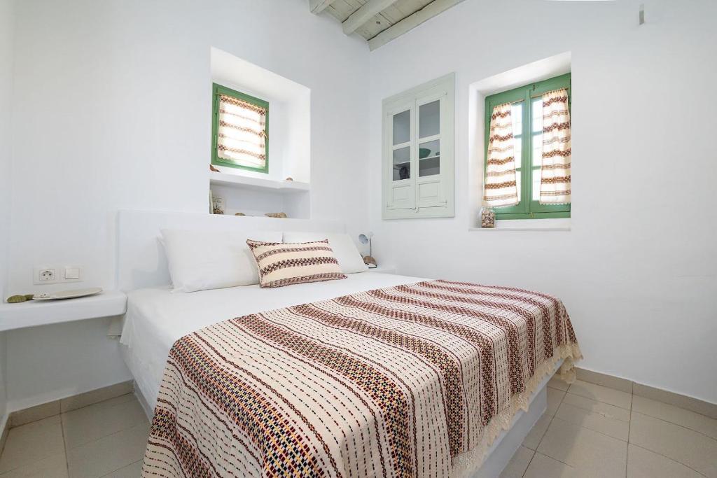 a white bedroom with a bed and two windows at Nymph Klido in Kanakis