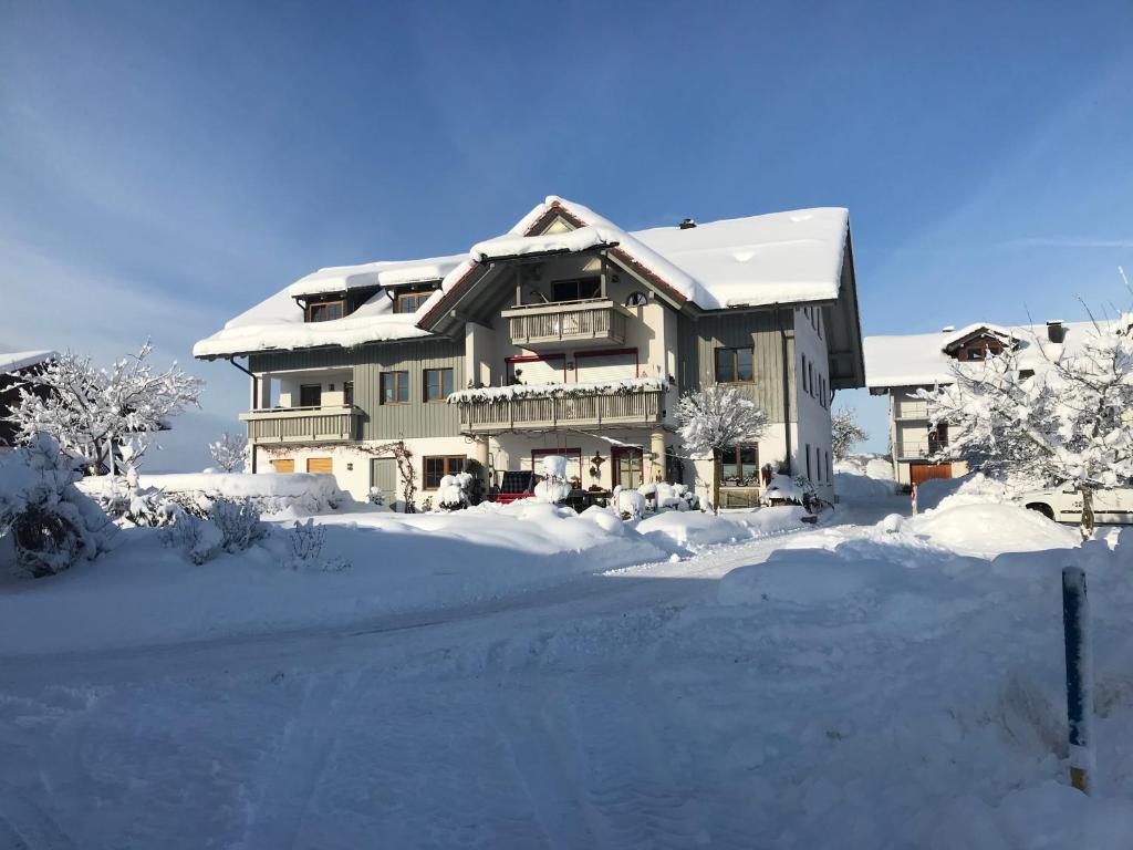ein großes Haus mit Schnee auf dem Boden in der Unterkunft Ferienwohnungen Allgäu-Bodensee in Sigmarszell