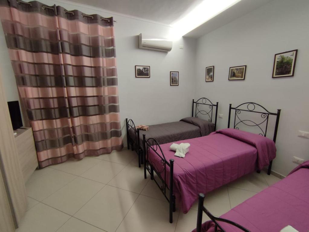 Ospitalità Baffone casa vacanze في Mercato: سريرين في غرفة ذات أغطية أرجوانية