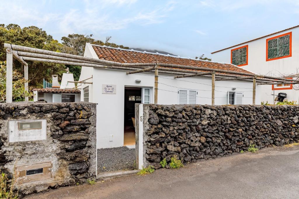 a white house with a stone fence in front of it at Retiro dos Cabritos in São Mateus