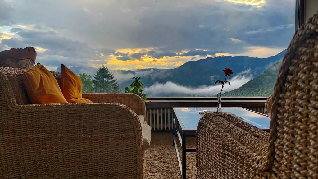 a person sitting in chairs on a balcony with a view of mountains at Villa Bello in Berchtesgaden