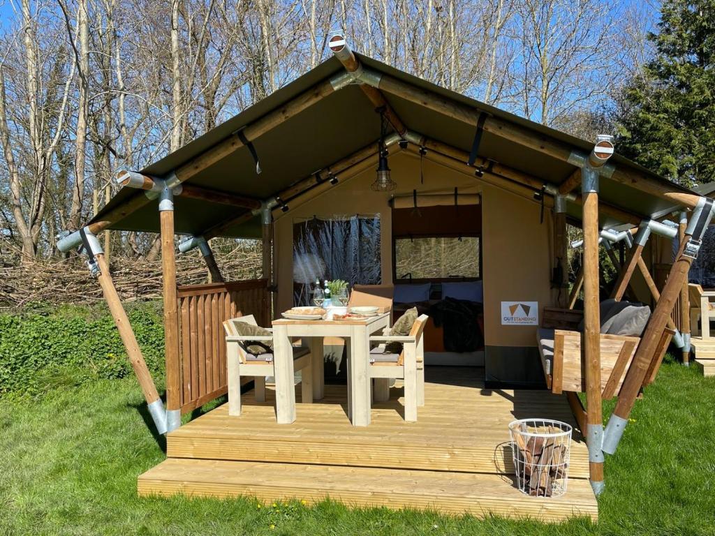 a gazebo with a table on a deck at Camping Zee van Tijd Holwerd in Holwerd
