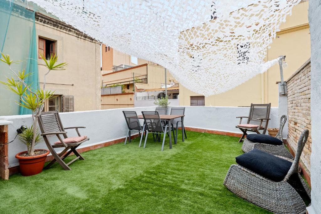 Un patio al aire libre con sillas, mesa y césped. en Hauzify I Novavila Centre Rooms, en Vilanova i la Geltrú