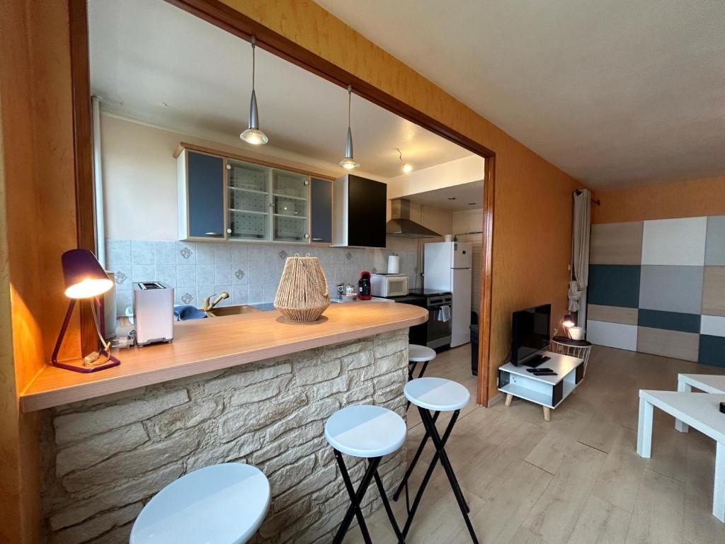 a kitchen with a counter and stools in a room at Le Pragmatique - Paris Parc Expo, logement entier in Vanves