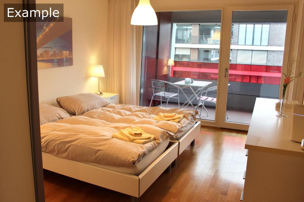 a bedroom with a bed and a table and a balcony at Residenz Senevita Westside in Bern
