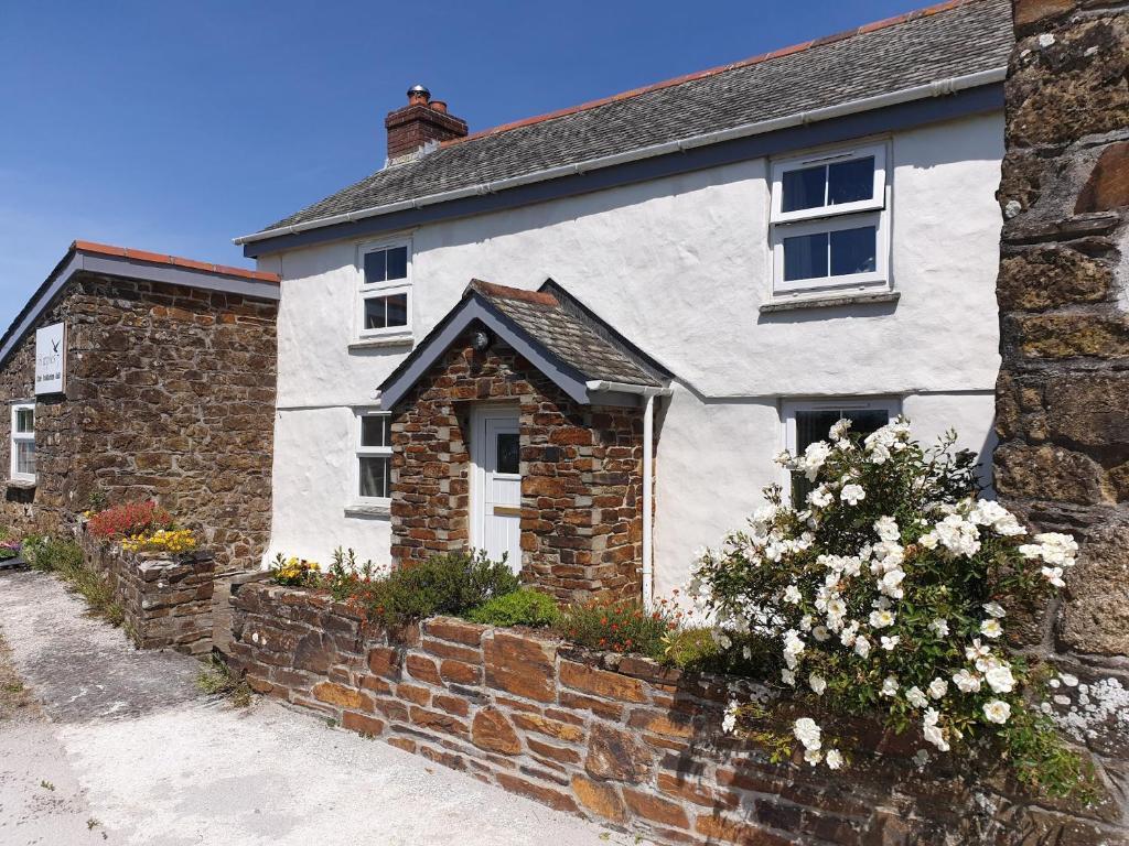 una casa blanca con una pared de ladrillo en Plain Street Cottage, en Port Isaac