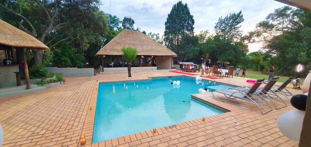 a swimming pool with chairs and a gazebo at Protea Ridge Guest Cottages and Conference Centre in Roodepoort