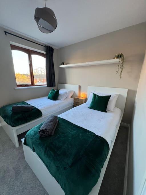 a bedroom with two beds with green sheets at Cosy Home In The Heart Of Sussex in Burgess Hill