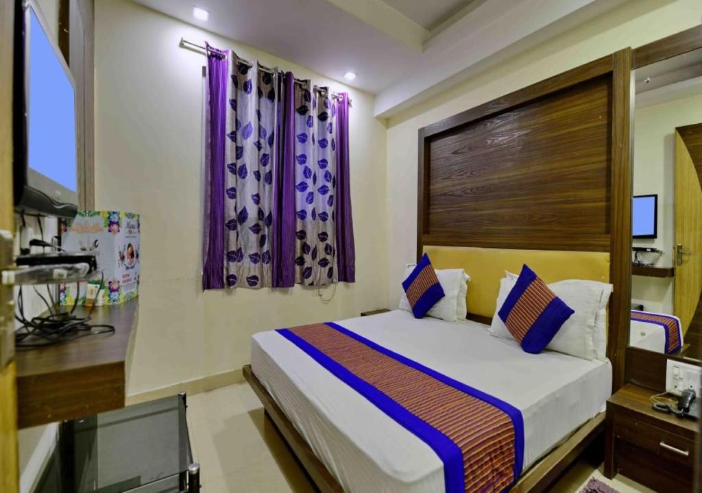 a bedroom with a large bed with purple curtains at Hotel Lembord Inn - BY - New Cashew Hotel in New Delhi