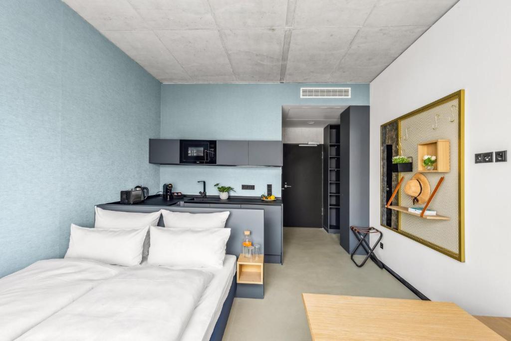 1 Schlafzimmer mit einem weißen Bett und einer Küche in der Unterkunft Nena Apartments München City - NEW OPENING 2024 in München