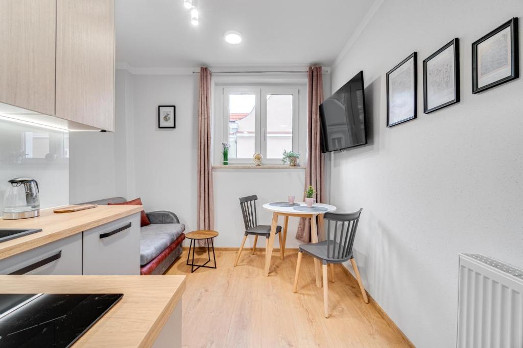 a kitchen and living room with a table and chairs at Apartamenty Franciszkańska in Opole
