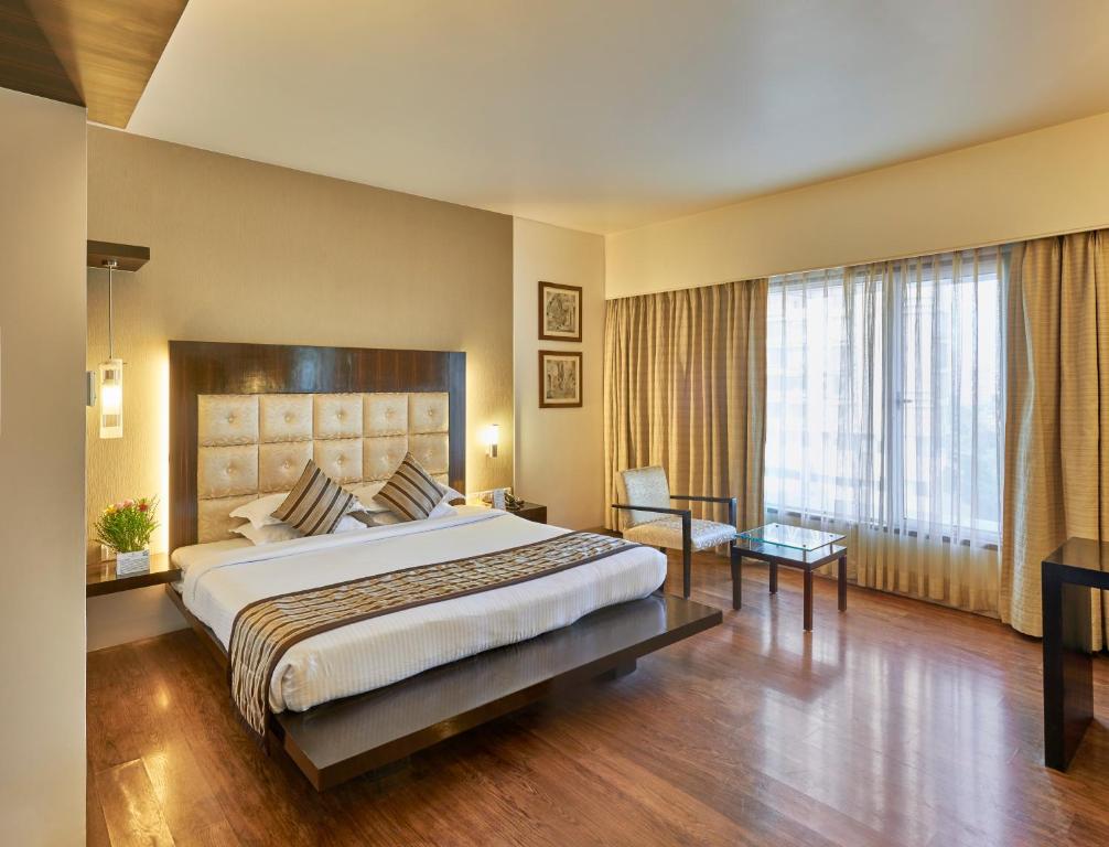 a bedroom with a large bed and a large window at Krishna Palace Hotel in Mumbai