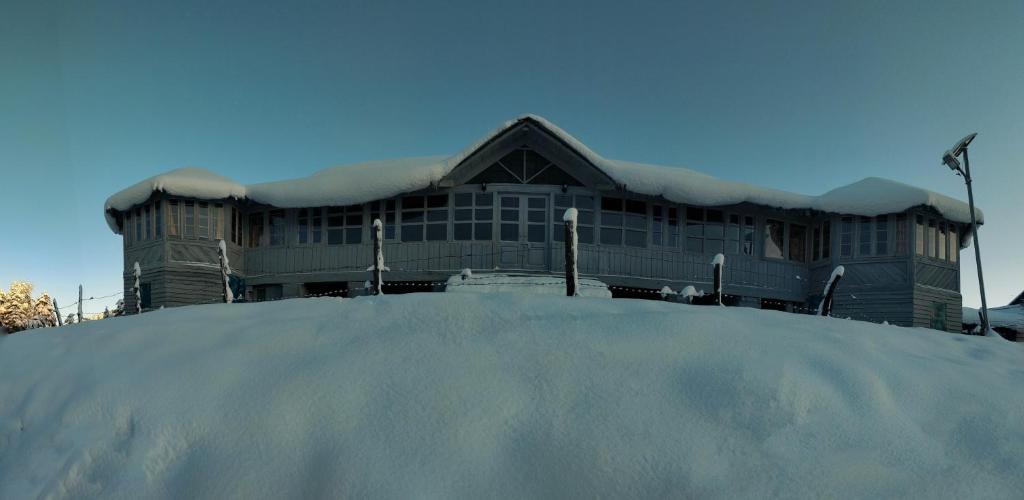 a building with a pile of snow in front of it at Black Bear Cottage khajjiar in Khajjiar 