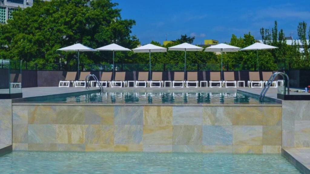 una piscina con sillas y sombrillas en Hotel Premium Chaves - Aquae Flaviae, en Chaves