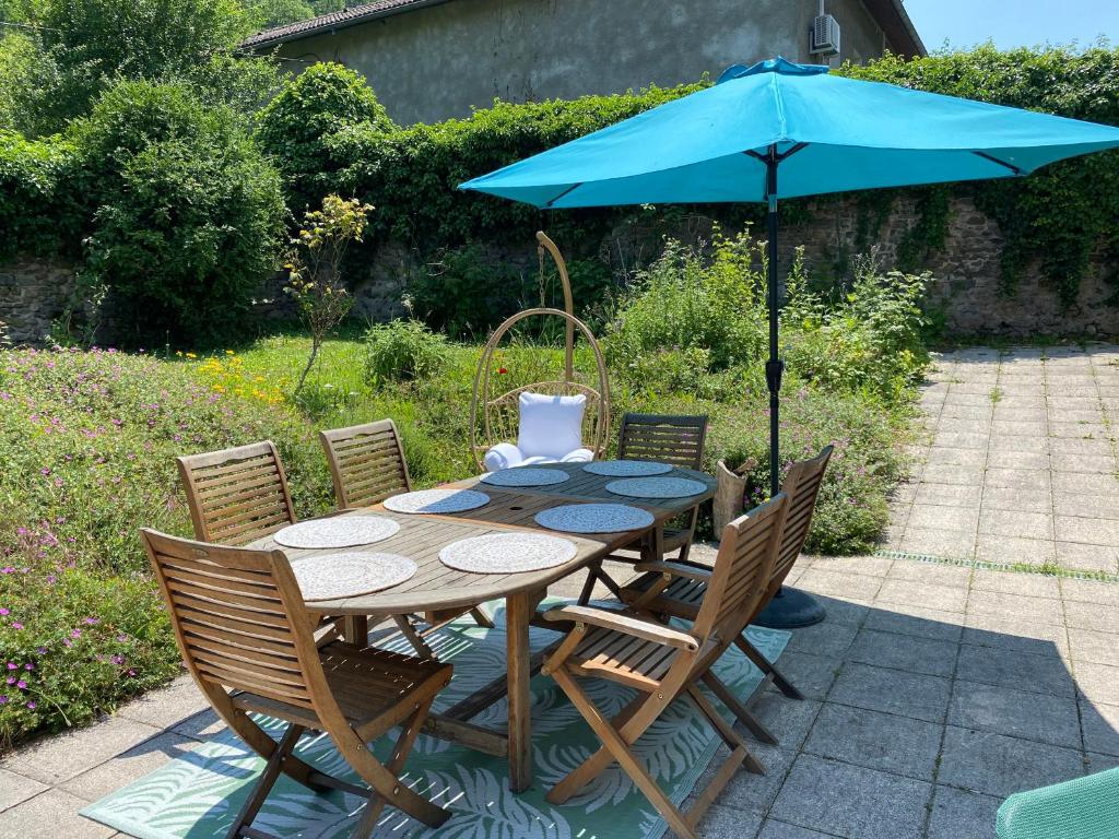 une table en bois avec un parasol bleu et des chaises dans l'établissement Maison Zen et Jacuzzi proche des passerelles himalayennes de Monteynard, à Vif
