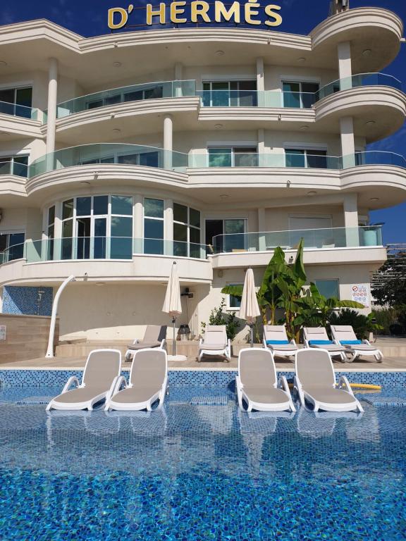 ein Hotel mit Stühlen und Sonnenschirmen neben einem Pool in der Unterkunft Apartments D'Hermes in Ulcinj