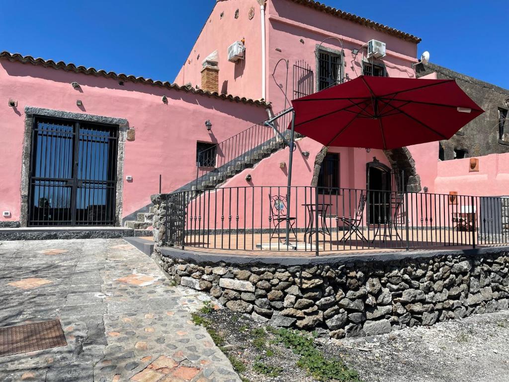 ein rosafarbenes Haus mit einem Tisch und einem Regenschirm in der Unterkunft Le Decime in Mascali