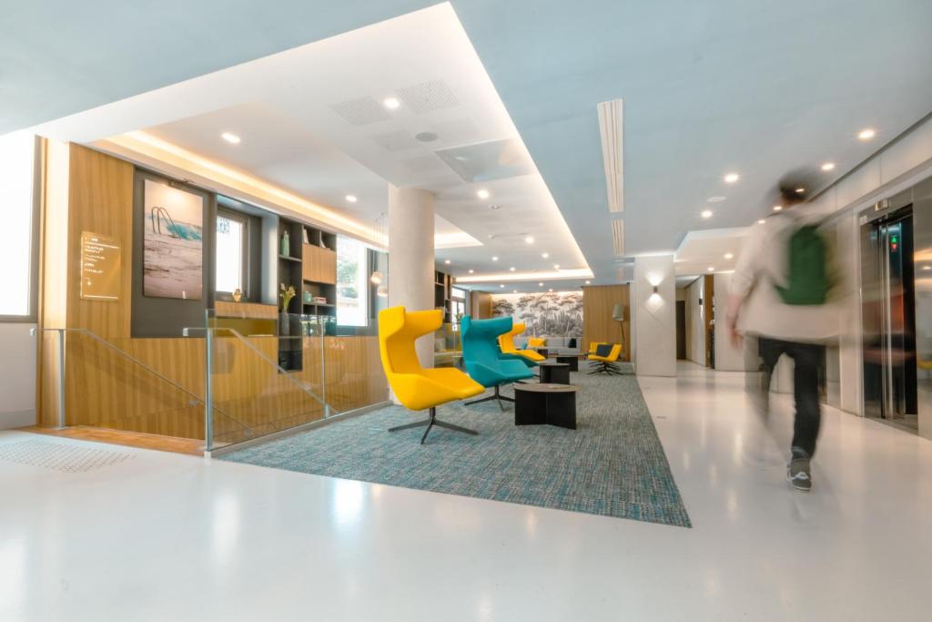 a person walking through a lobby with chairs and tables at Nemea Appart Hotel Cannes Palais in Cannes