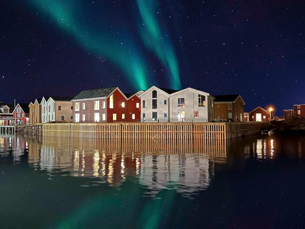 een stad met het noorderlicht in de lucht boven het water bij Henningsvær Bryggehotell - by Classic Norway Hotels in Henningsvær