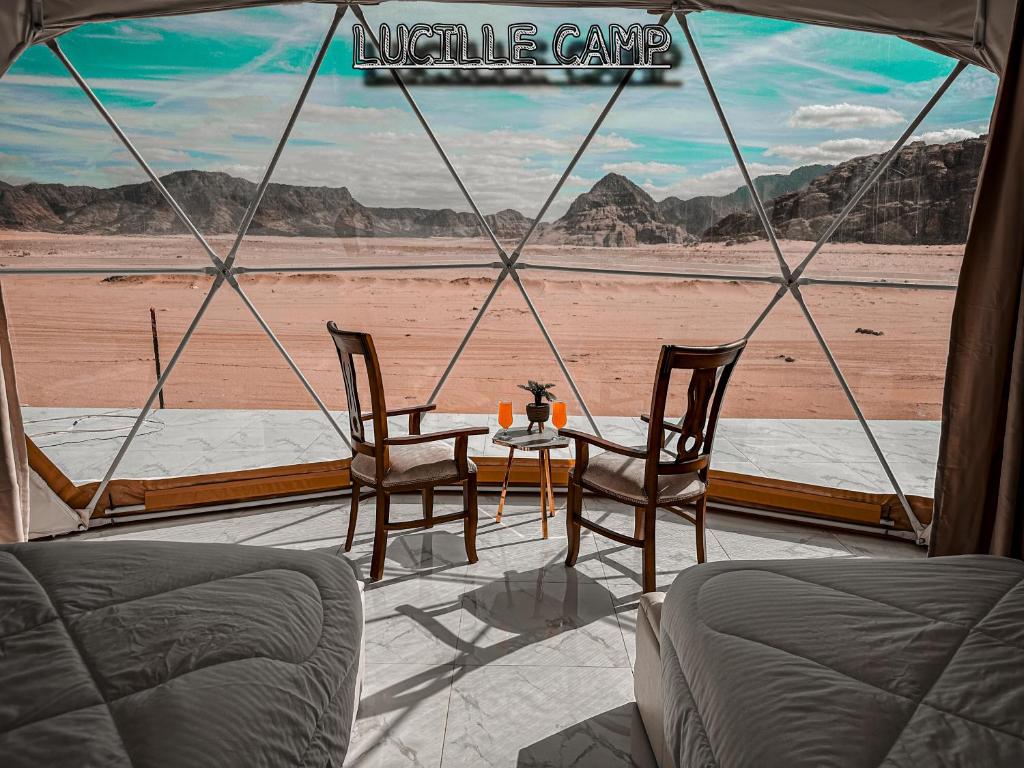 Rum Lucille Luxury camp في وادي رم: خيمة مع طاولة وكراسي وإطلالة على الصحراء