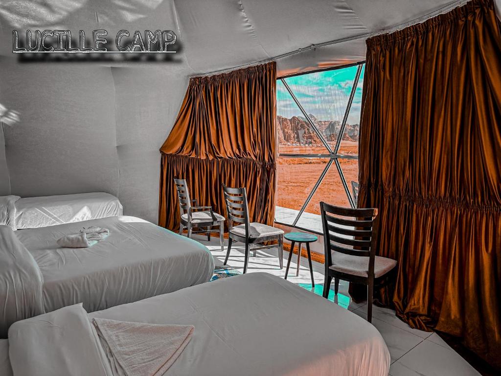a room with two beds and chairs and a window at RUM LUCILLE lUXURY CAMP in Wadi Rum