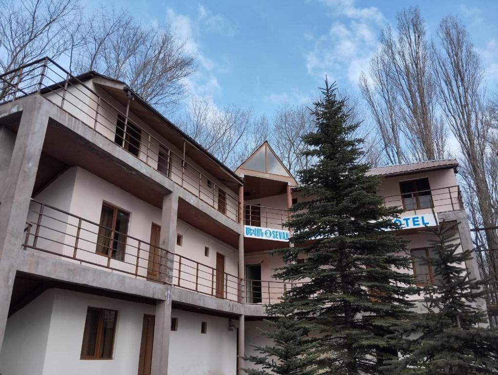 un bâtiment avec un pin devant lui dans l'établissement Севан 3 Ветерок, à Sevan
