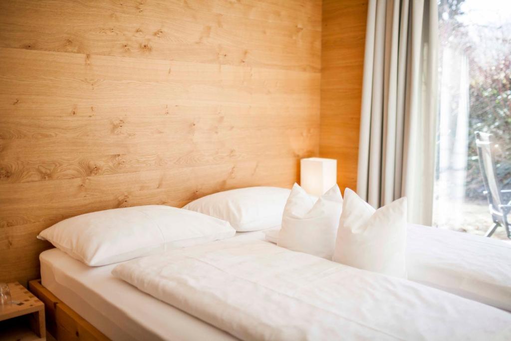 Bett mit weißen Kissen in einem Zimmer mit Fenster in der Unterkunft Steindls Boutique Favourite in Sterzing