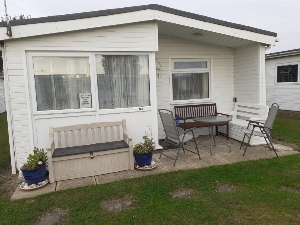 a patio with a bench and a table and chairs at Sundowner 3 Bed Chalet in Hemsby Great Yarmouth in Great Yarmouth