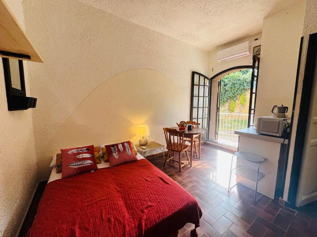 une chambre avec un lit rouge et une table avec des chaises dans l'établissement Studio 5 PORTO LUMIO, à Lumio