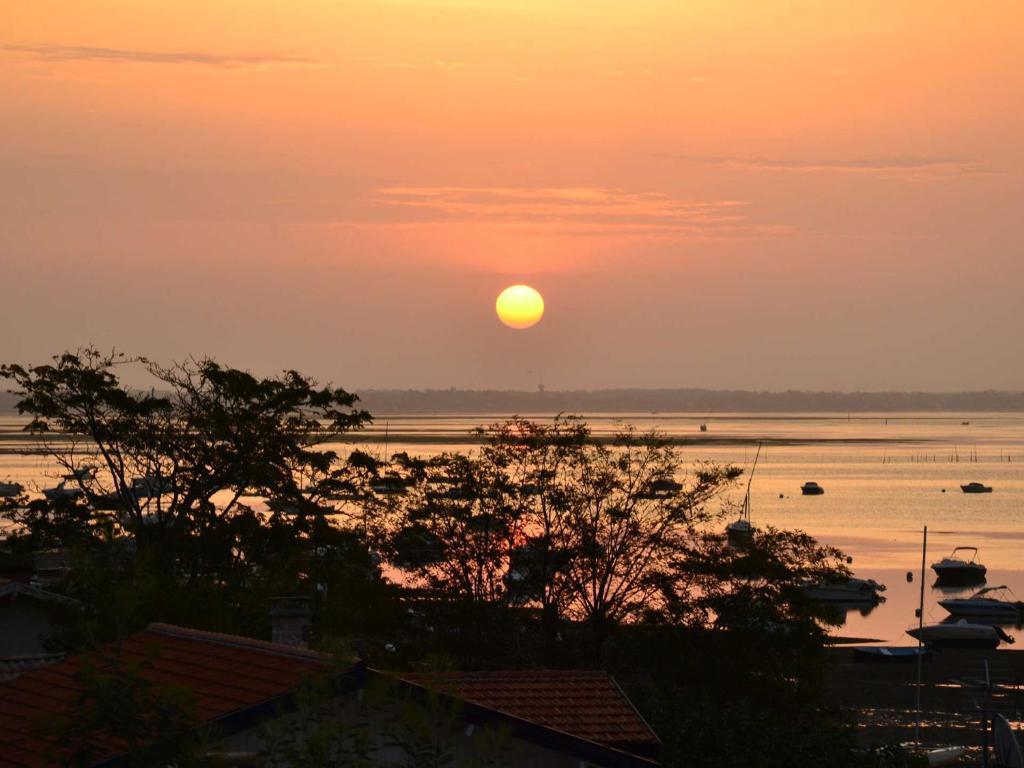 un coucher de soleil sur une étendue d'eau avec des bateaux dans l'établissement Grande villa avec jacuzzi à La Pointe aux Chevaux - FR-1-736-23, à Lège-Cap-Ferret