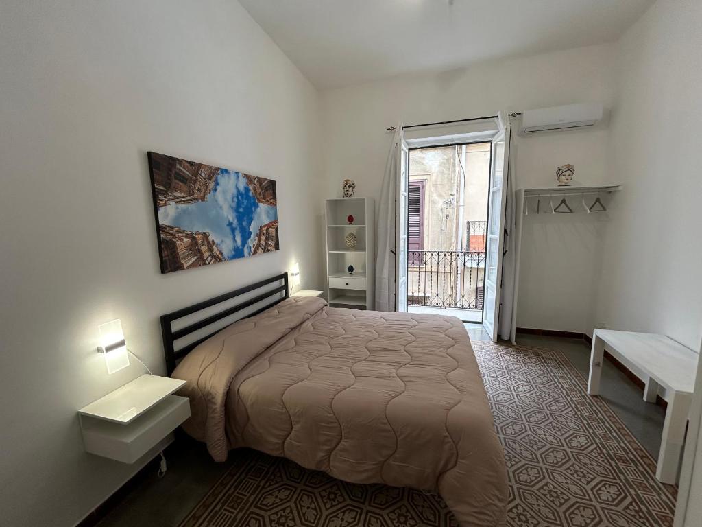 a bedroom with a large bed and a balcony at Le Trottole Apartment in Palermo