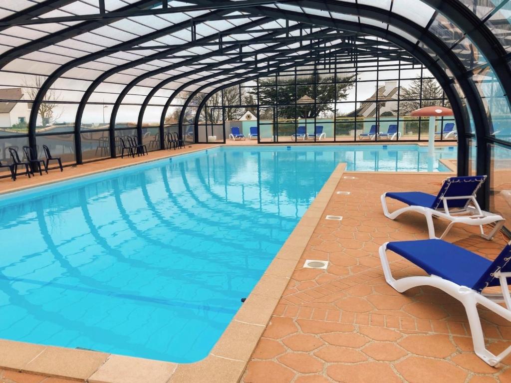una gran piscina con 2 sillas en un edificio en Camping la Corniche, en Plozévet