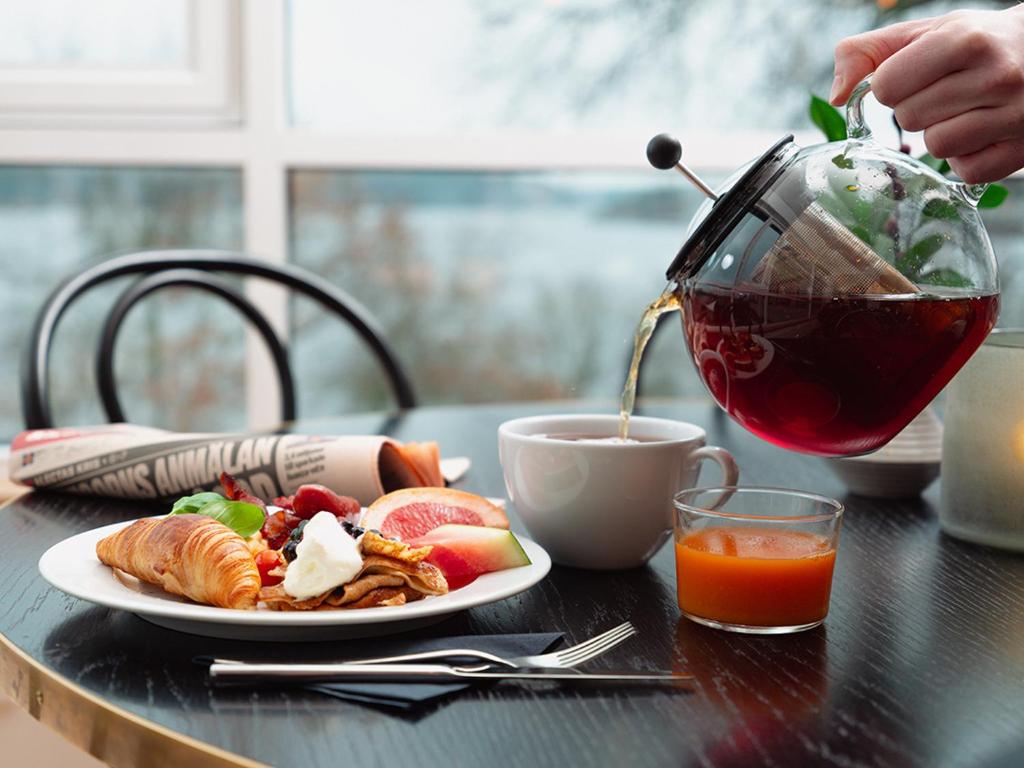 einen Tisch mit einem Teller Essen und einer Tasse Kaffee in der Unterkunft Rönneberga Konferens in Lidingö