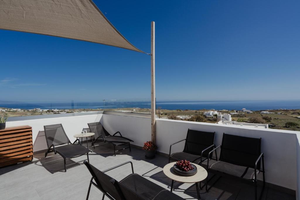 eine Terrasse mit Stühlen und Tischen und Meerblick in der Unterkunft The Vine Suites in Vourvoúlos