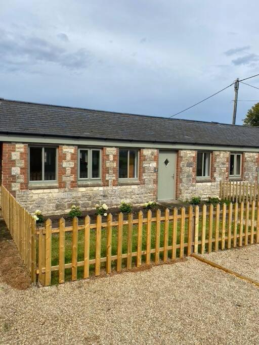 a brick house with a wooden fence in front of it at Pretty cottage near Cirencester in Purton