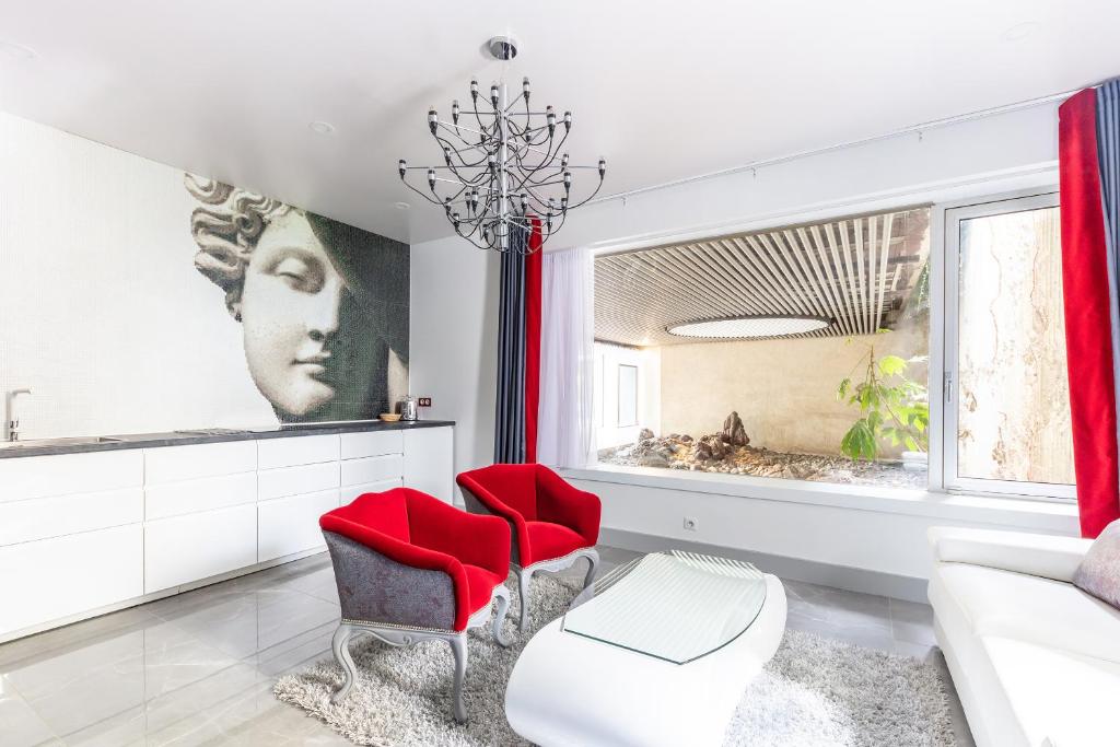 a living room with red chairs and a chandelier at MARAIS - Elegant Flat in Old Paris in Paris