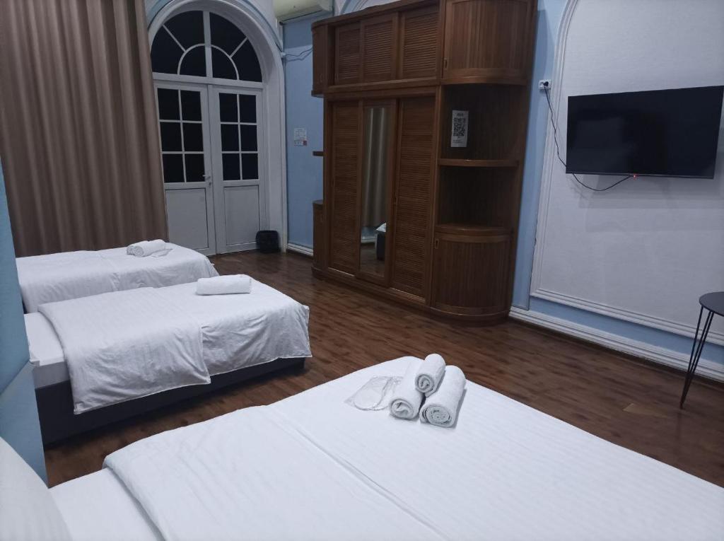 a hotel room with two beds and a tv at GOLDEN TRIP Hotel in Yunusobod