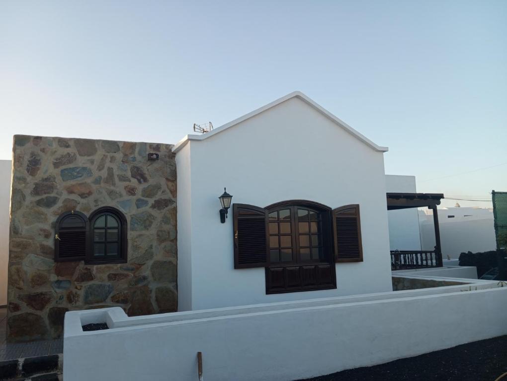 a white house with black windows and a stone wall at Casa Siempreviva in Teguise