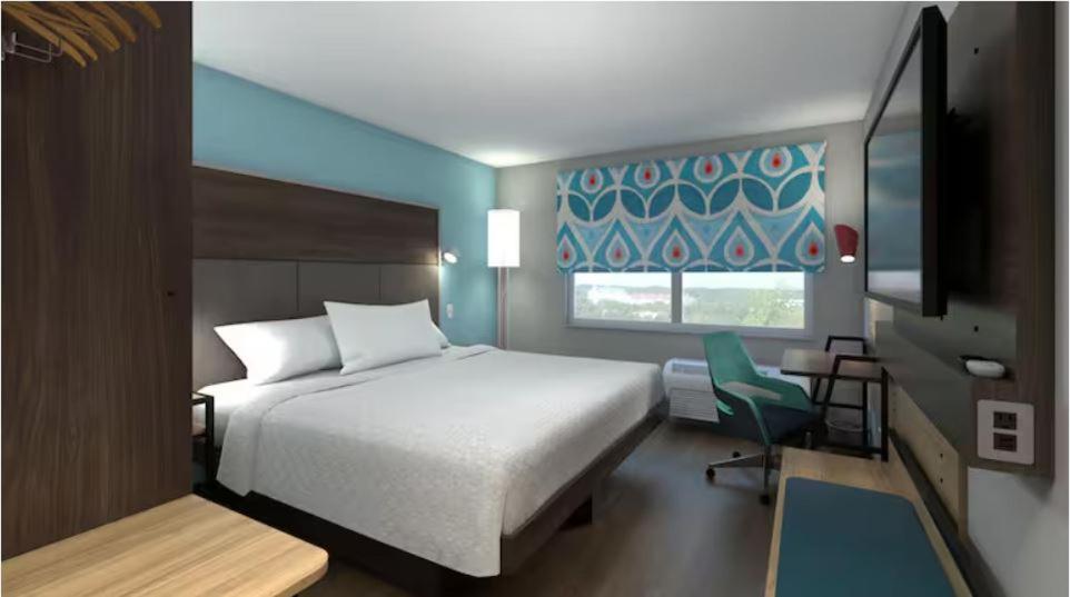 a bedroom with a white bed and a green chair at Tru By Hilton Rogers Bentonville in Rogers