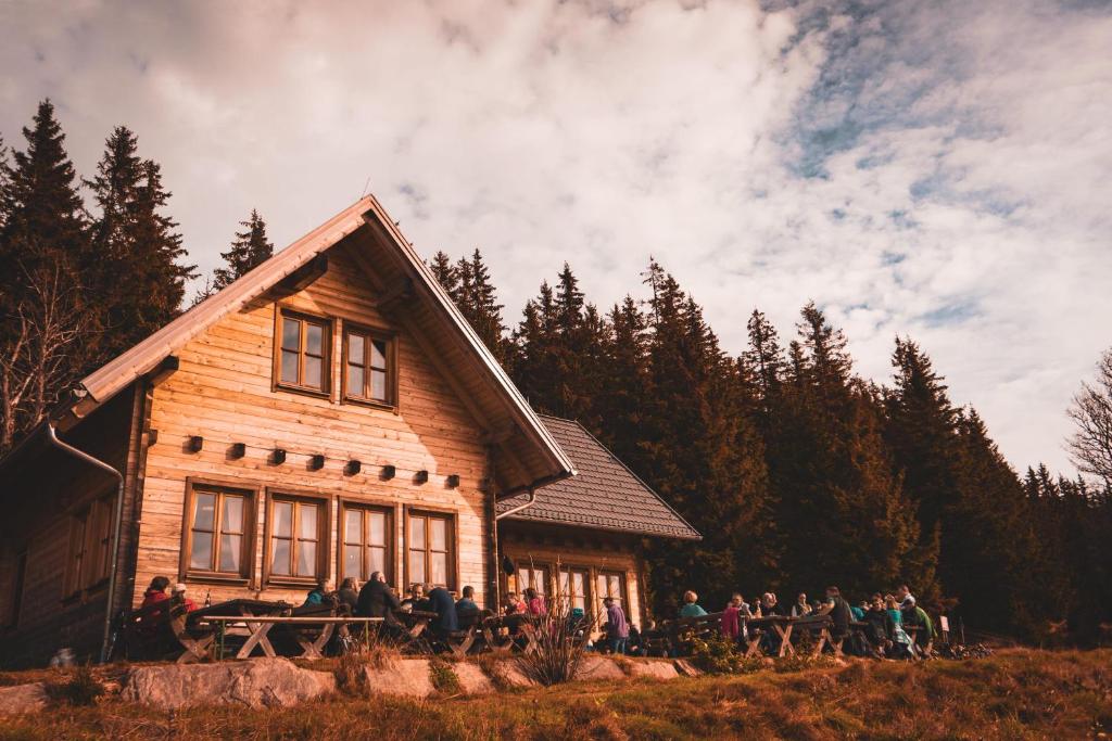 een groep mensen die buiten een houten huis staan bij Glatzl Trahütten Alm in Sankt Lorenzen am Wechsel