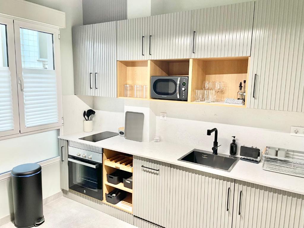 a kitchen with white cabinets and a sink and a microwave at Estudio Regenta Con Parking privado in Oviedo