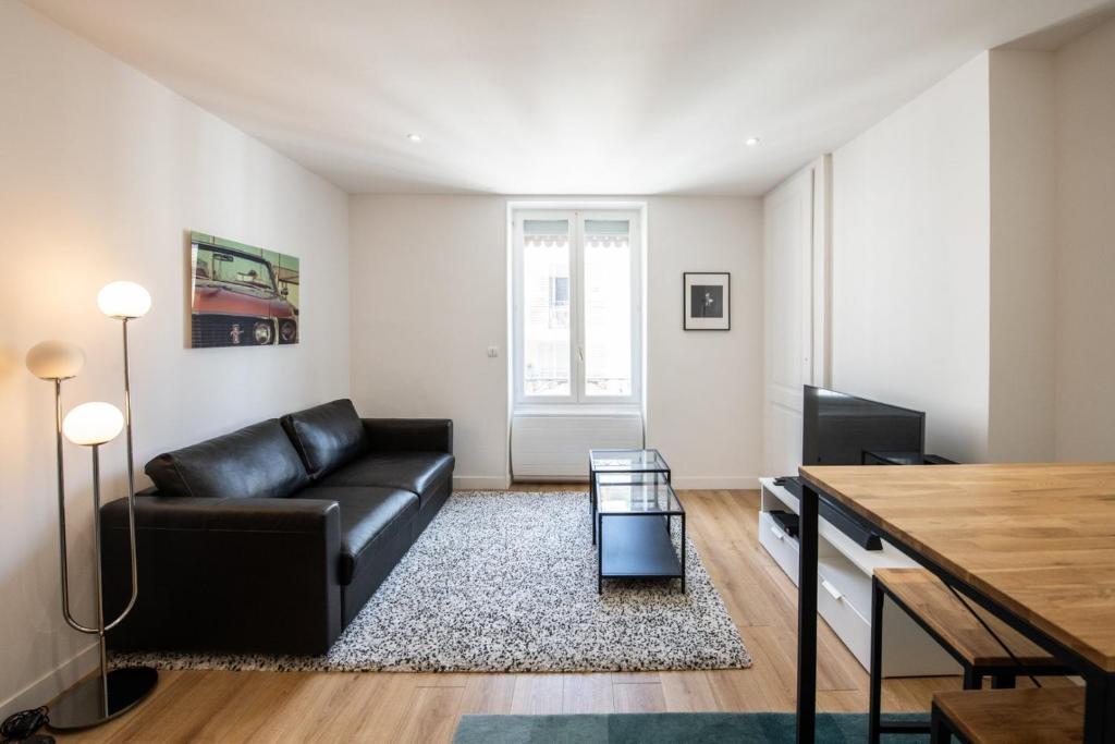 un salon avec un canapé en cuir noir et une table dans l'établissement Lac Ness - Bel appartment central Part-Dieu, à Lyon