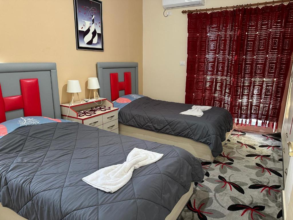 twee bedden in een slaapkamer met rode gordijnen bij Sarf Farm Libohove in Libohovë
