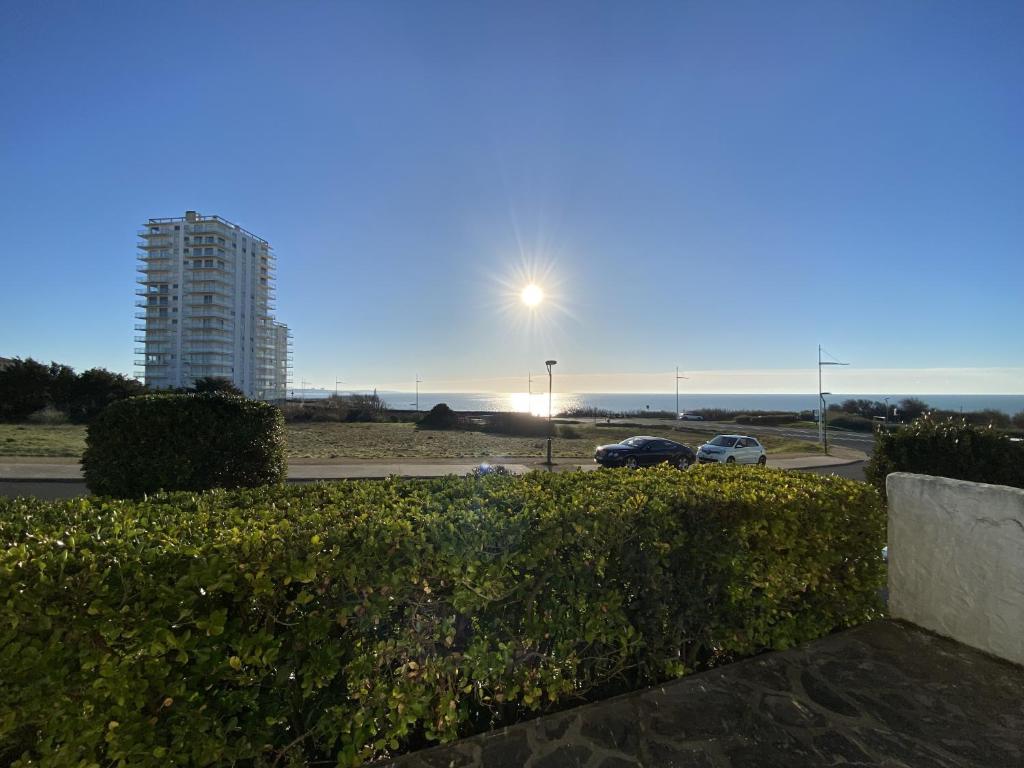 - une vue sur un parking avec un bâtiment et l'océan dans l'établissement Maison face mer La Chaume, à Les Sables-dʼOlonne