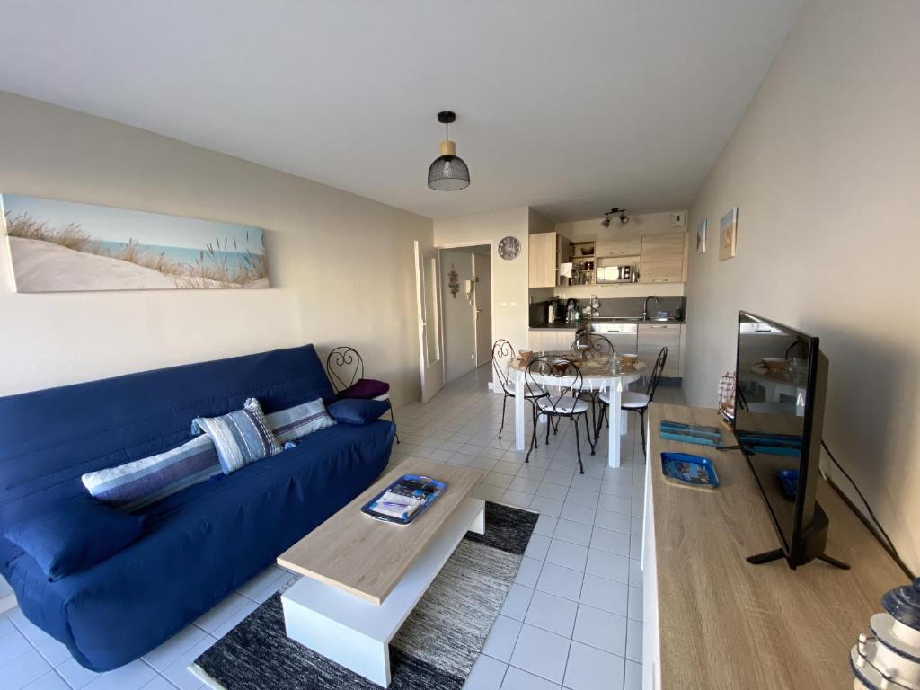 un salon avec un canapé bleu et une table dans l'établissement Appartement proche plage - BALCON, à Les Sables-dʼOlonne