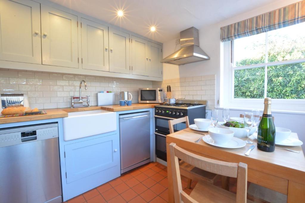 a kitchen with white appliances and a wooden table at 1 South Cottages in Thorpeness